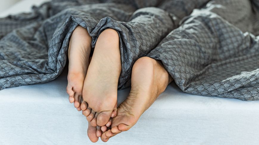 Les pieds d'un homme et d'une femme au bout d'un lit durant un moment tendre